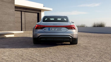 Die Heckansicht des Audi S e-tron GT auf einer gepflasterten Einfahrt. Die durchgehende LED-Lichtleiste und der sportliche Diffusor betonen das dynamische Design.