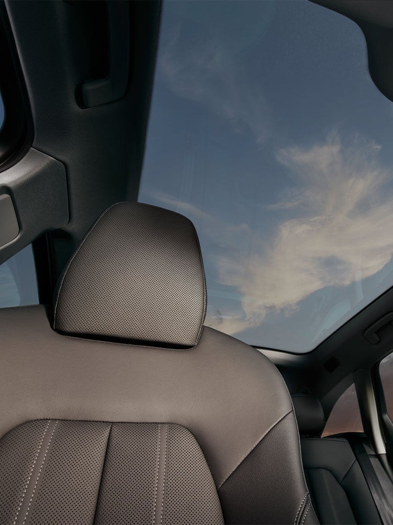 Blick von innen durch das Panorama-Glasdach des Audi A5 Avant mit sichtbarem Dachhimmel und Vordersitz.