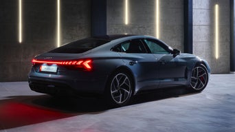 The RS e-tron GT seen from a slanted rear perspective as it parked in the driveway of a building.