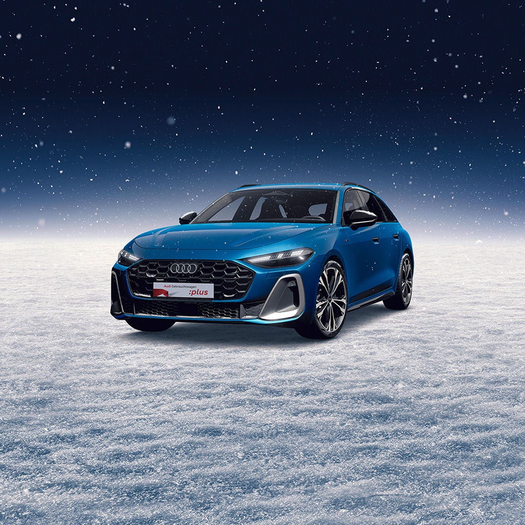 Ein blauer Audi A5 steht auf einem schneebedeckten Untergrund, während es schneit.