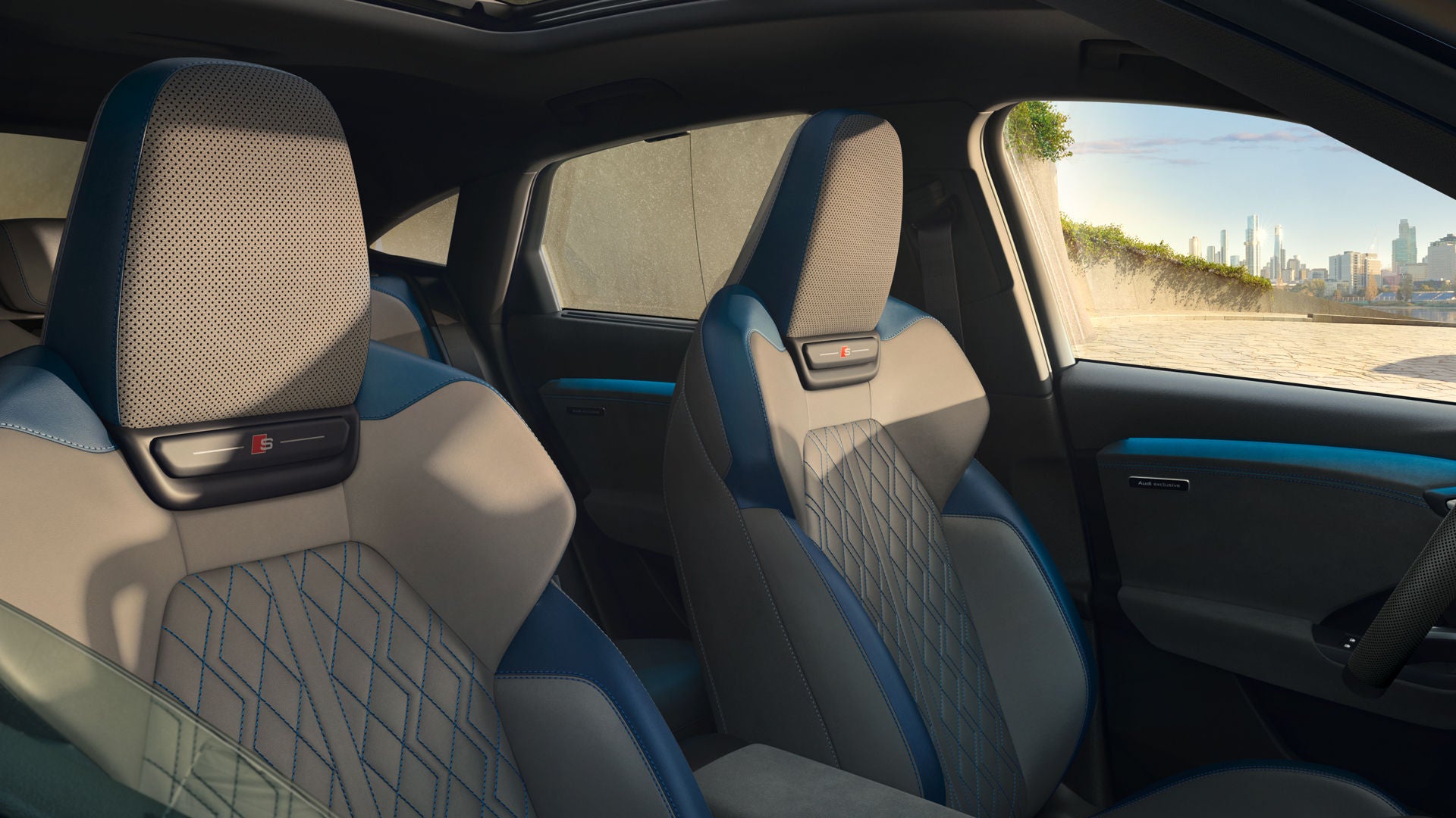 Die vorderen beiden Sitze des Q6 Sportback e-tron aus der Perspektive des halb geöffneten Beifahrerfensters. Das Interieur erscheint in dem Designpaket Jetgrau/Ozeanblau.