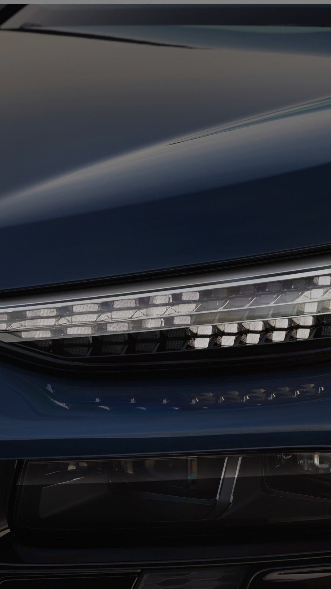 Close-up of a sleek blue car's headlight, featuring a modern, angular design and LED elements.