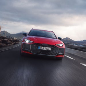 The RS 5 Avant is seen from the front driving on a mountain road.