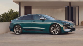 Der S6 Sportback e-tron steht im leicht schrägen Seitenprofil vor einem modernen Haus.