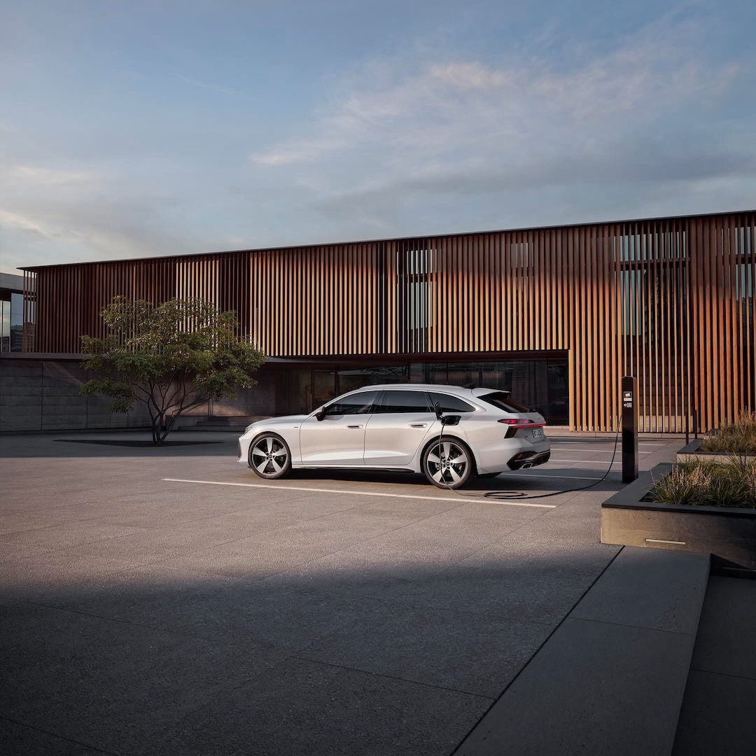 Audi A6 Avant e-hybrid parcheggiata e collegata a una colonnina di ricarica