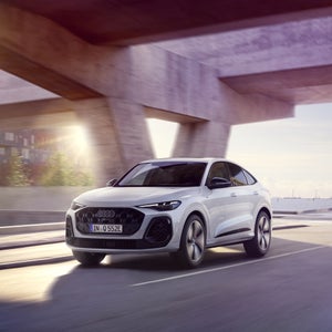 Een witte Q5 Sportback e-hybrid rijdt onder een viaduct.