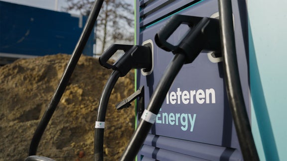 Een Audi A3 Sportback e-hybrid, schuin van achteren gezien tegen een donkere achtergrond, aangesloten op een snellaadstation.