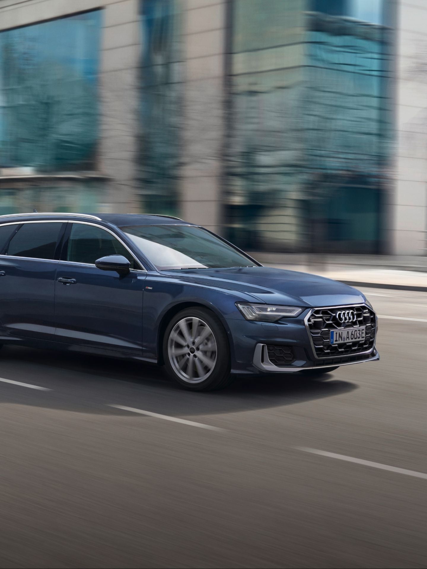 A blue car driving on an urban road with blurred background.