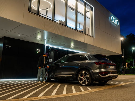 A man charges his car at the charging hub at night