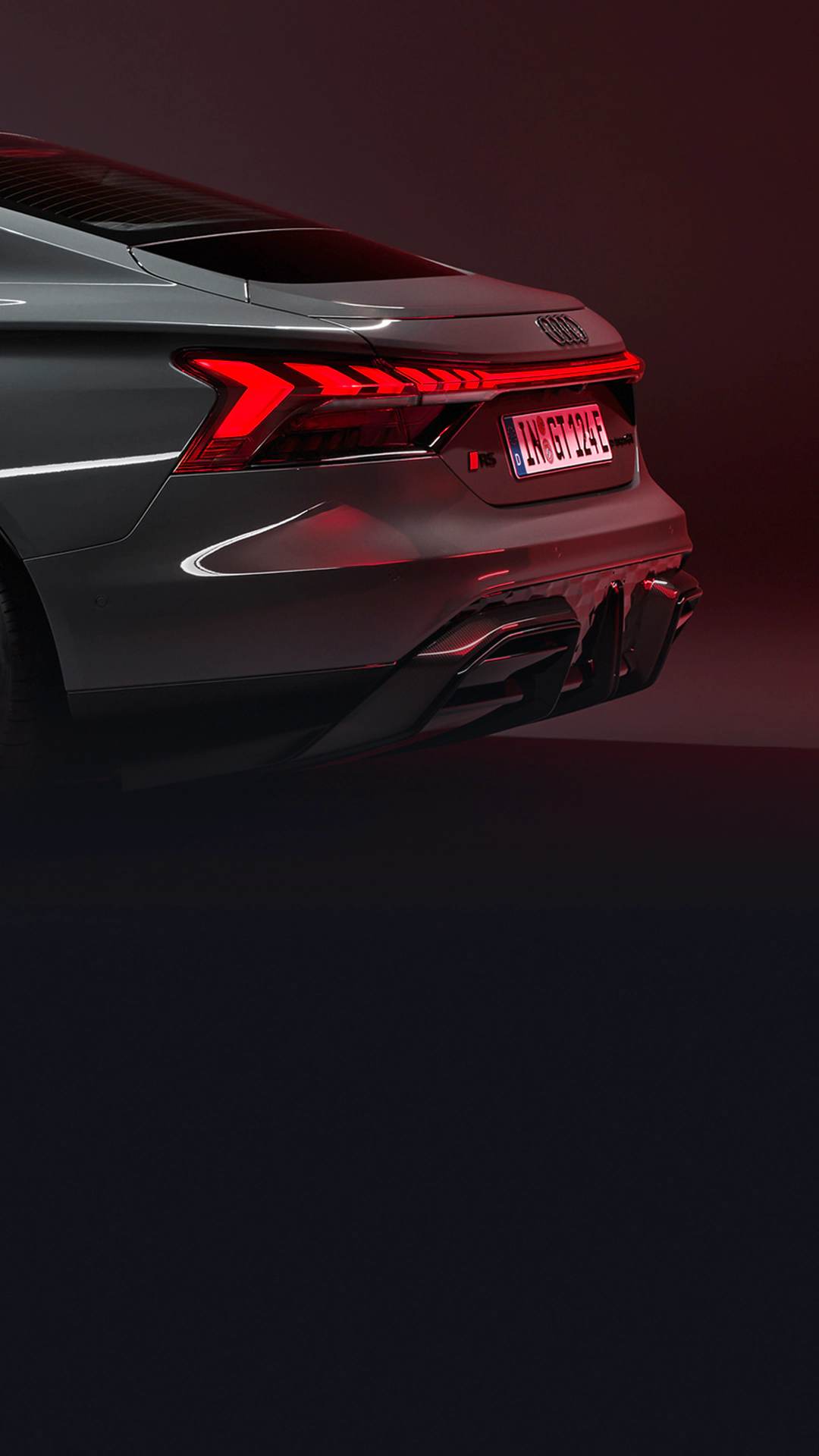 Grey Audi RS e-tron GT rear with red taillights, on dark background.