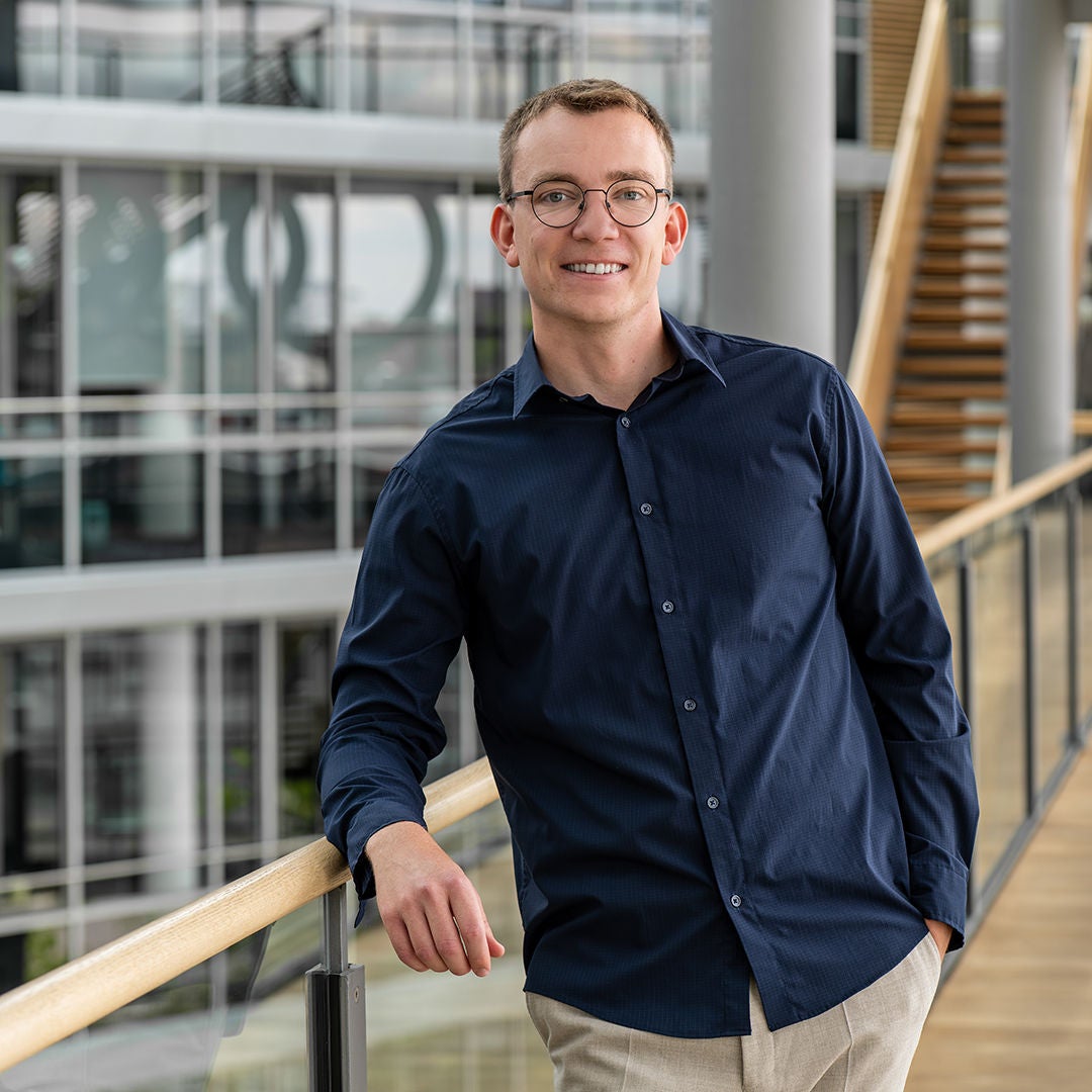Christian Ohmstedt is leaning against a railing and smiling at the camera