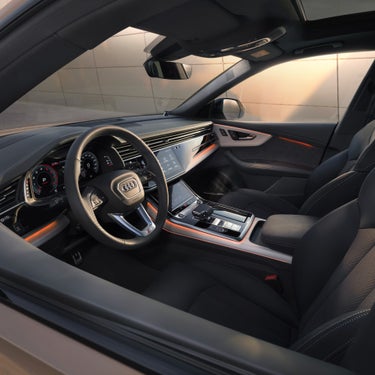 Car interior with leather seats, audi steering wheel, and modern dashboard.