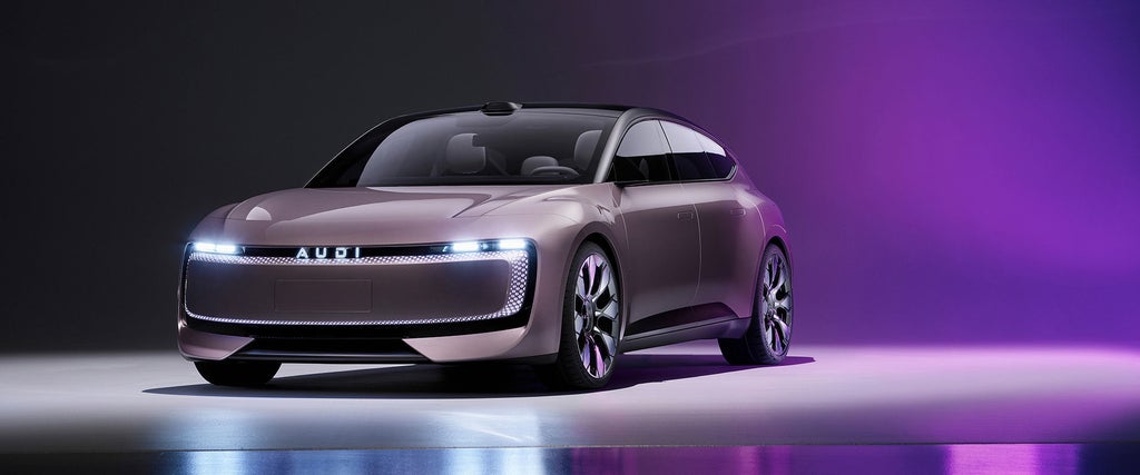 Das Audi-Konzeptfahrzeug mit futuristischem Design und durchgehender LED-Lichtsignatur steht in einer dunklen Studio-Umgebung mit violetter Beleuchtung, die sich auf dem Boden spiegelt.        