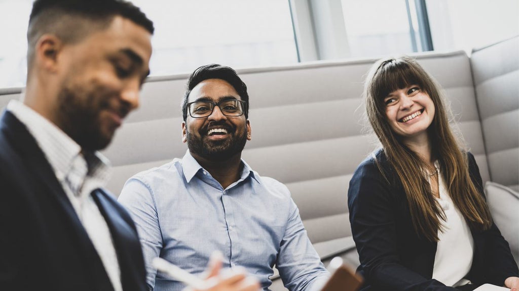 Three people laughing and wearing business clothes