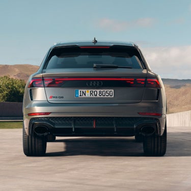 Rear view of Audi RS Q8 facing mountain range.