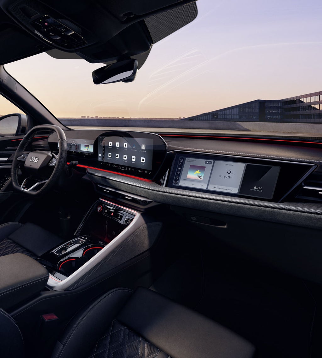 Zicht door het passagiersraam op de cockpit van de Audi SQ5 SUV. Onder meer het panoramadisplay, het MMI-display voor de passagier en de rode sfeerverlichting zijn zichtbaar.
