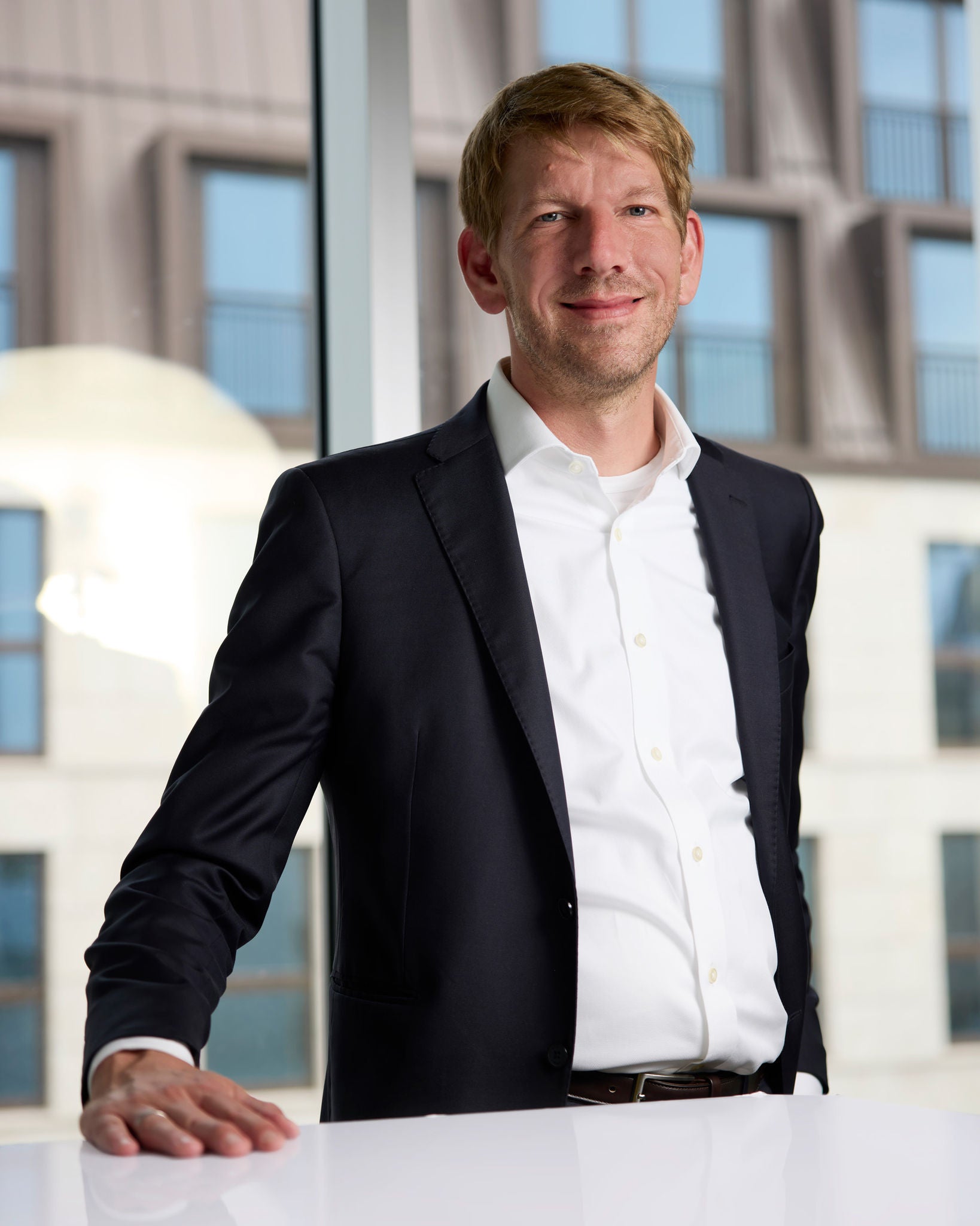 Julio Schuback, Leiter Corporate Content House der Audi Kommunikation steht vor einem Tisch und schaut in die Kamera