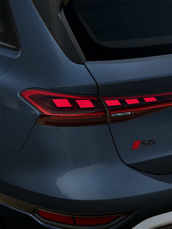 Nahaufnahme des Hecks eines dunkelblauen Audi S6 Avant e-tron mit leuchtenden LED-Rückleuchten und deutschem Kennzeichen.