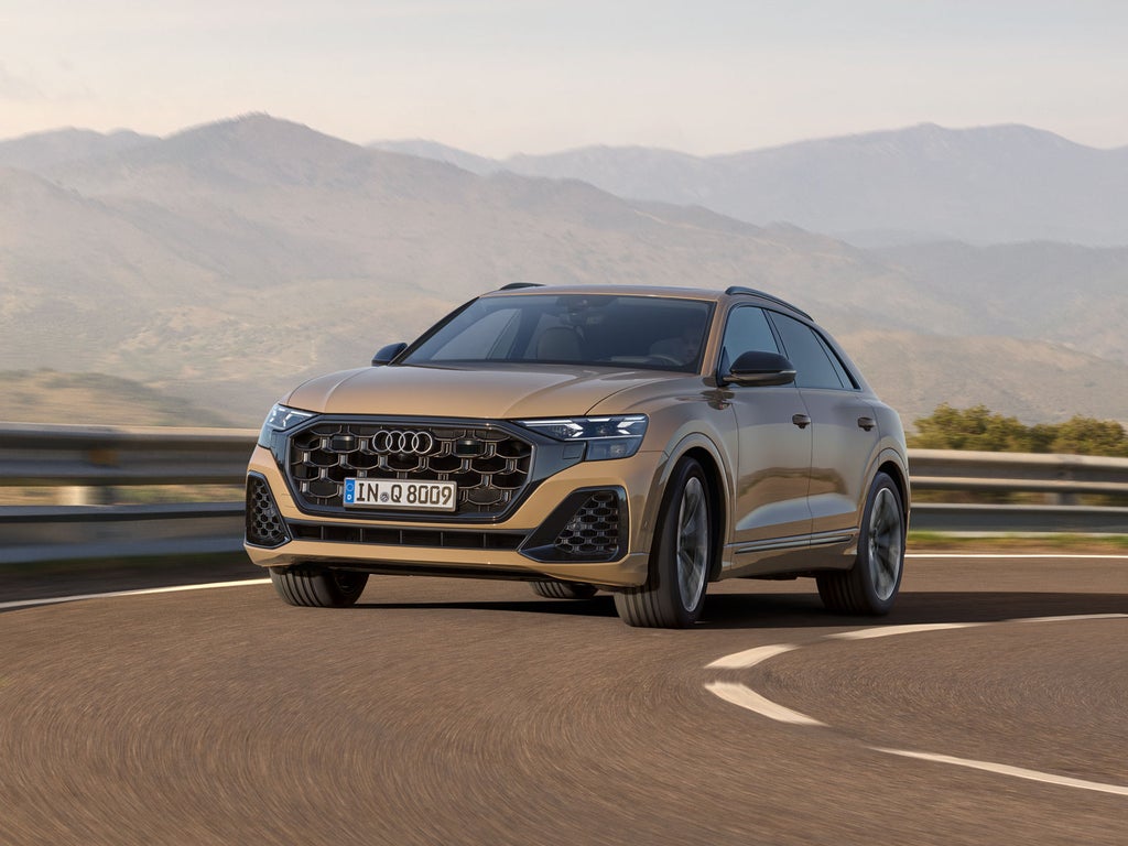 Der Q8 SUV passiert eine Kurve, im Hintergrund eine bergige Landschaft bei wolkenlosem Himmel.