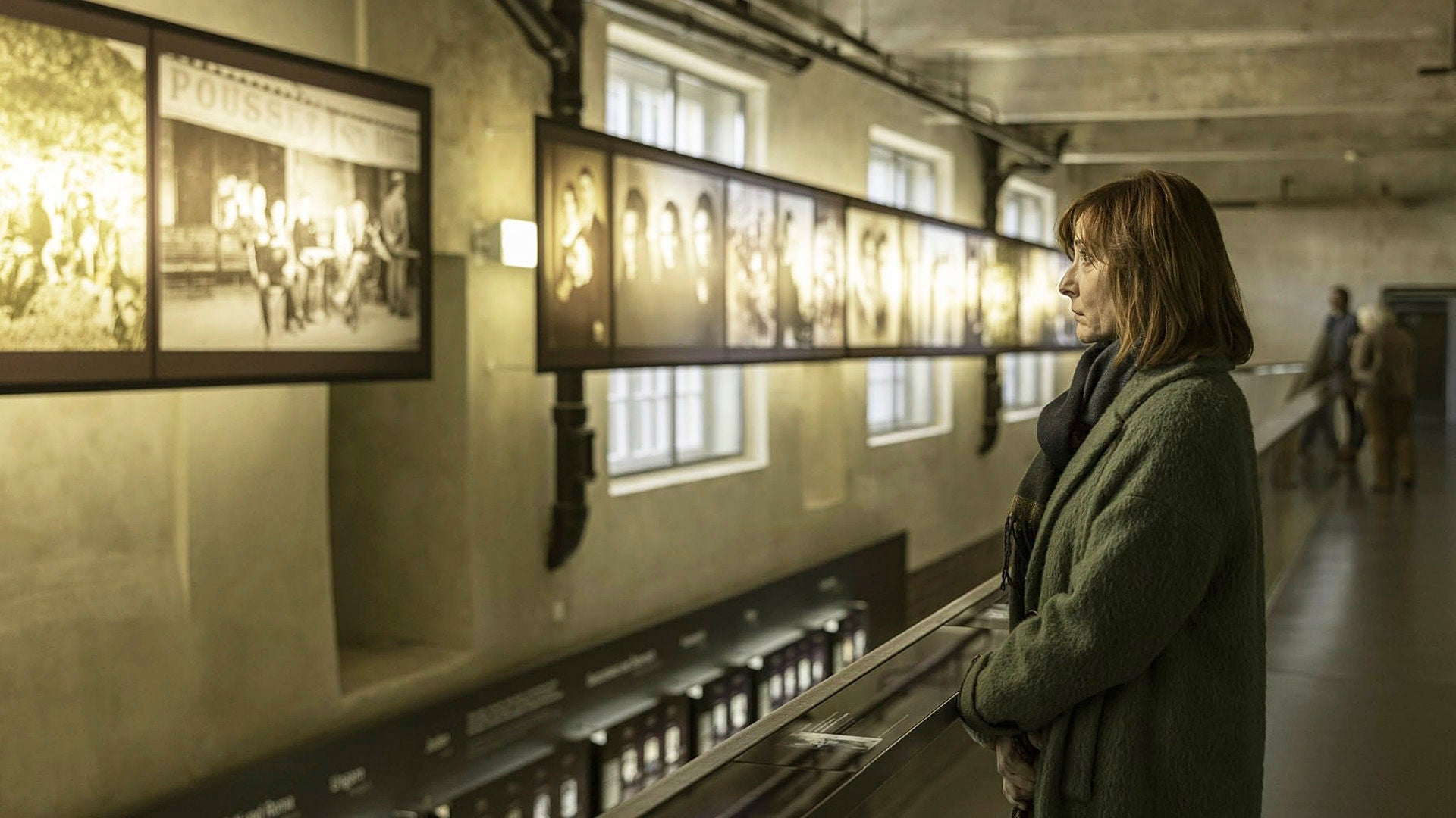 Eine Frau betrachte in einer alten Halle die Bilder einer Holocaust Ausstellung.