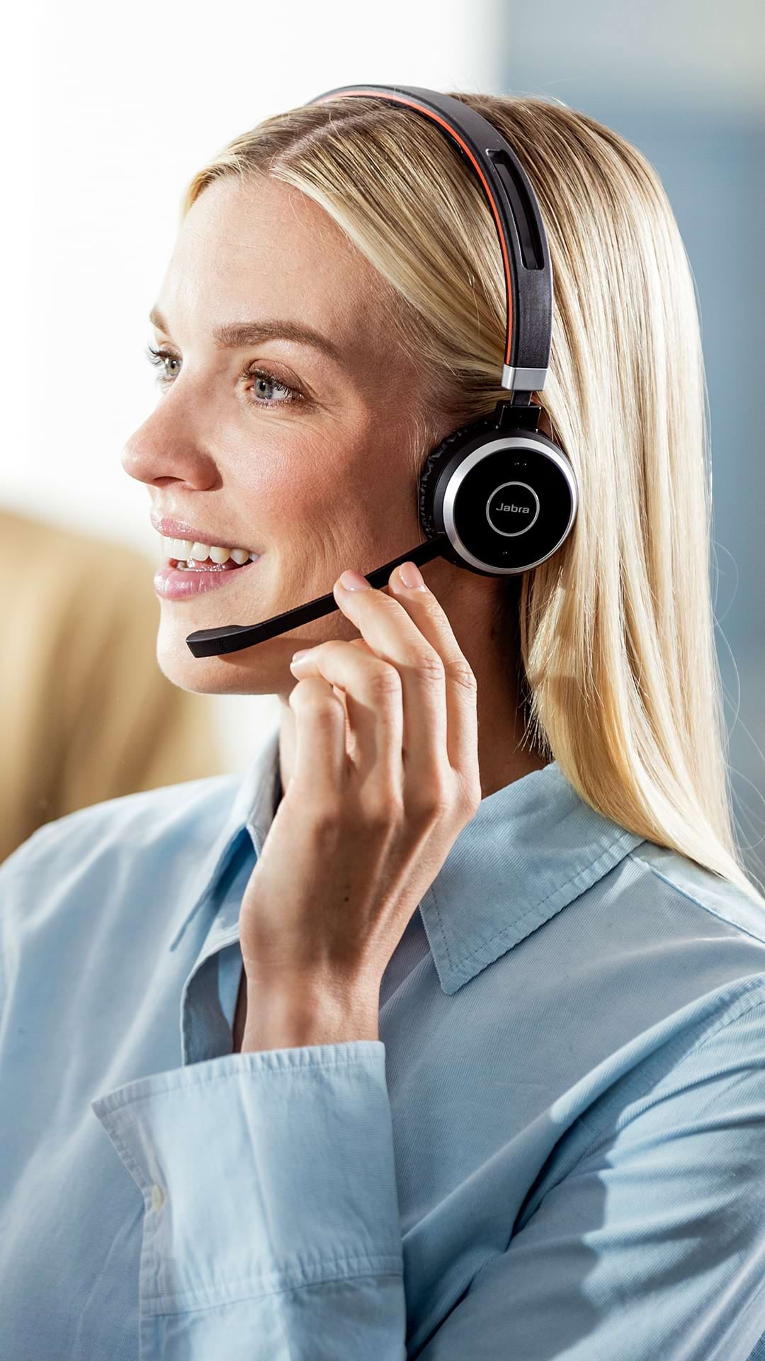 A blonde woman talking via a wireless headset
