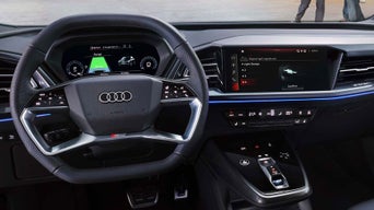 Innenraum eines Audi mit digitalem Cockpit, Multifunktionslenkrad und zentralem Touchscreen mit Fahrzeugfunktionen.