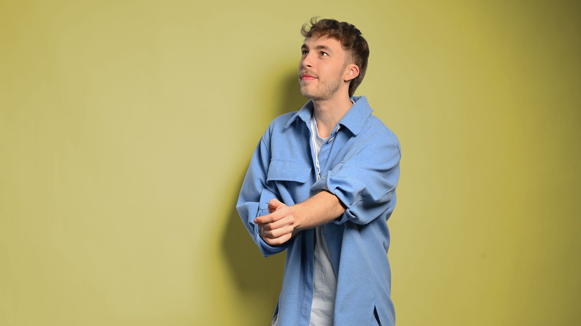 Julian schaut nach links und richtet den Ärmel seines Hemdes