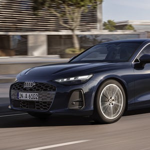 Die A6 Limousine fährt im schrägen Frontprofil auf einer Straße in der Innenstadt.