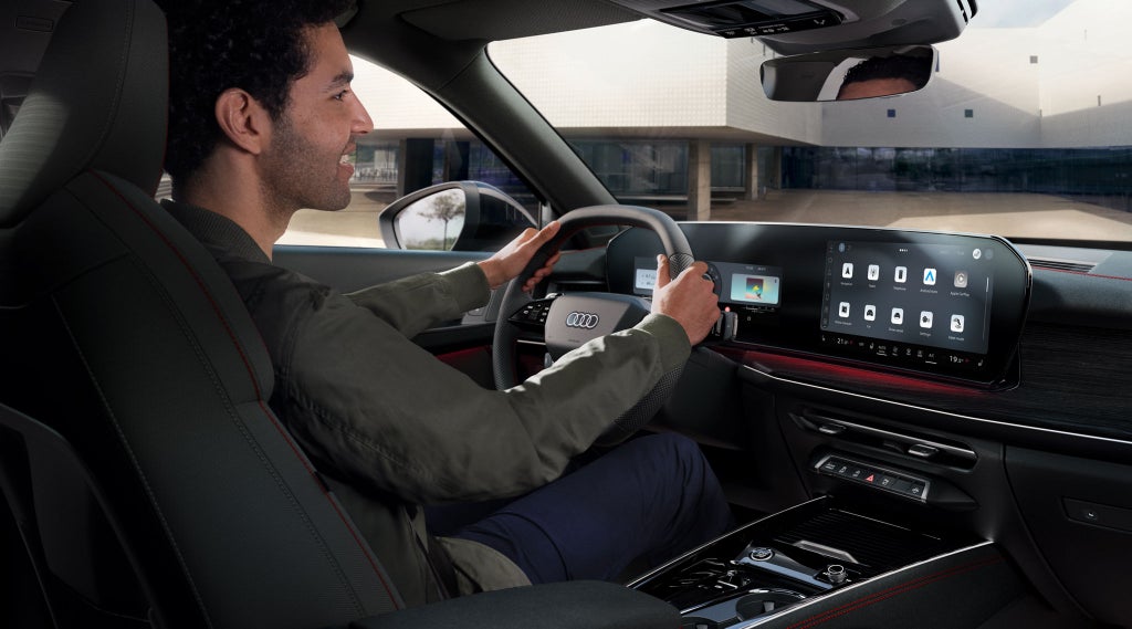 Vista angolata del cockpit della Q3 Sportback da dietro, con un giovane seduto al volante.