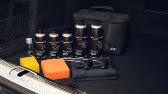Autopflege-Set mit Audi-Flaschen, Schwämmen, Tüchern und Tasche im Kofferraum.