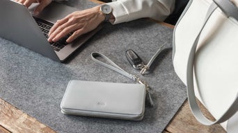 Nahaufnahme eines Arbeitsplatzes mit Laptop, Audi-Schlüssel, grauer Geldbörse und Tasche.