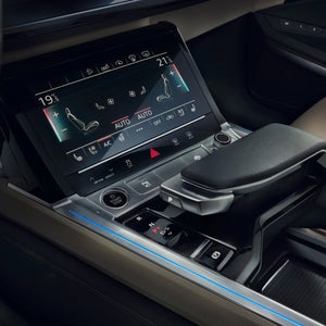 Sleek car interior featuring a modern infotainment system, control buttons, gear shift, and ambient lighting.