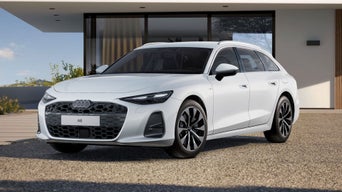 The A6 Avant with its sloping front profile, parked in front of a modern residential building.