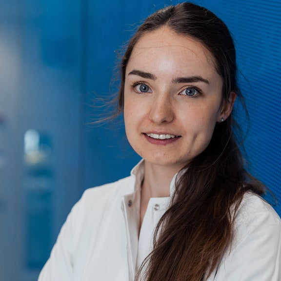 Menschen stehen im Kreis. Vor ihnen hockt ein Mann und zeigt ihnen Dinge.