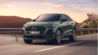 Dark green Audi SUV driving through a lake view road.