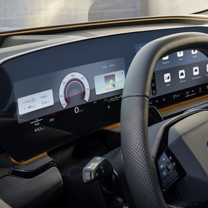 Das Cockpit und Fahrerdisplay aus der Perspektive des Fahrerfensters. Unter der Windschutzscheibe ist das Interaktionslicht in Sonnengelb zu erkennen.