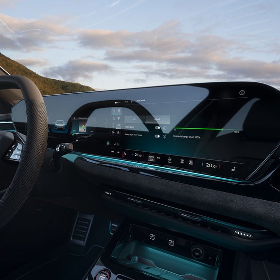 Car dashboard with a sleek digital display showing hybrid mode options. Steering wheel and lush landscape outside, conveying luxury and innovation.