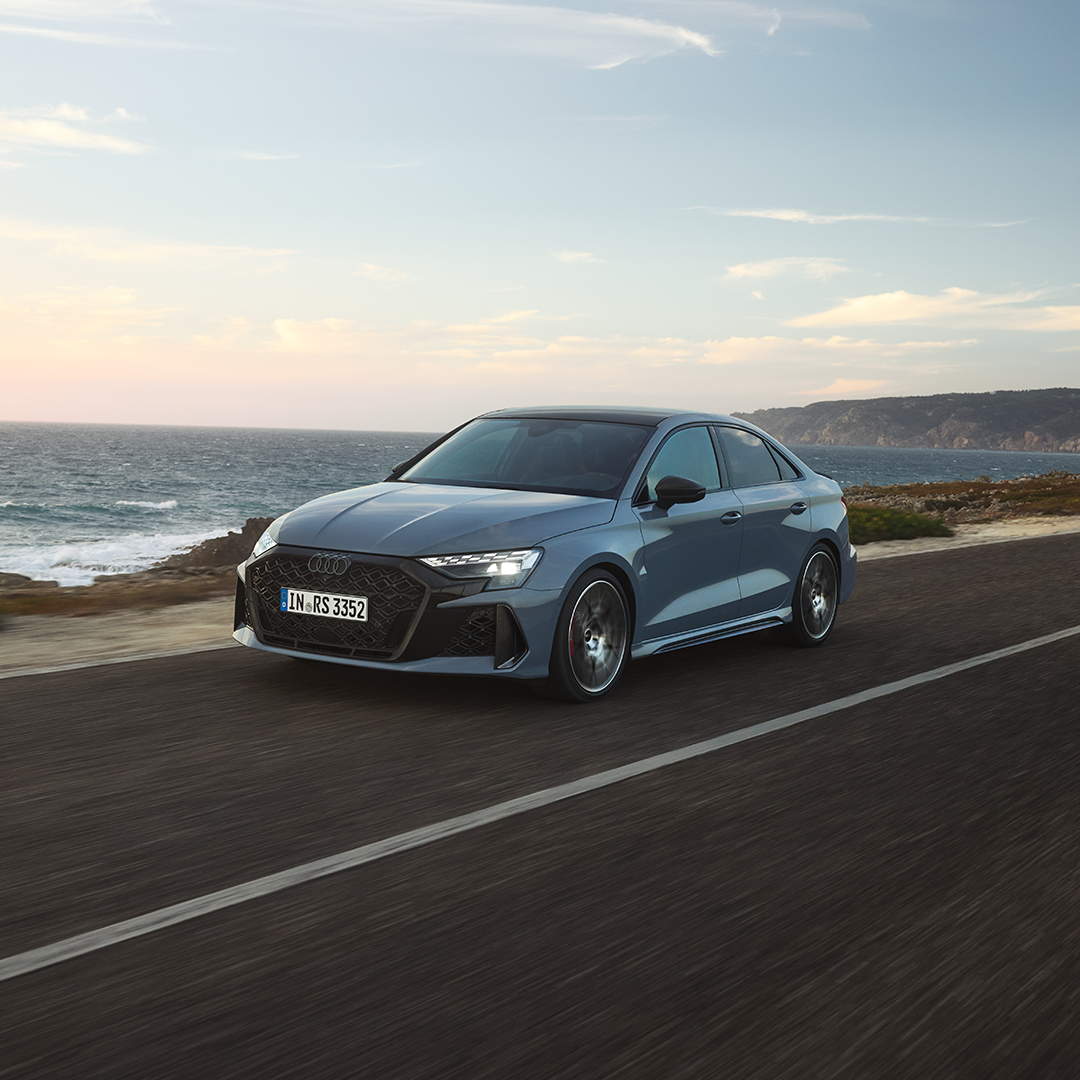 Two Audi cars facing each other side by side with beautiful sky at the back
