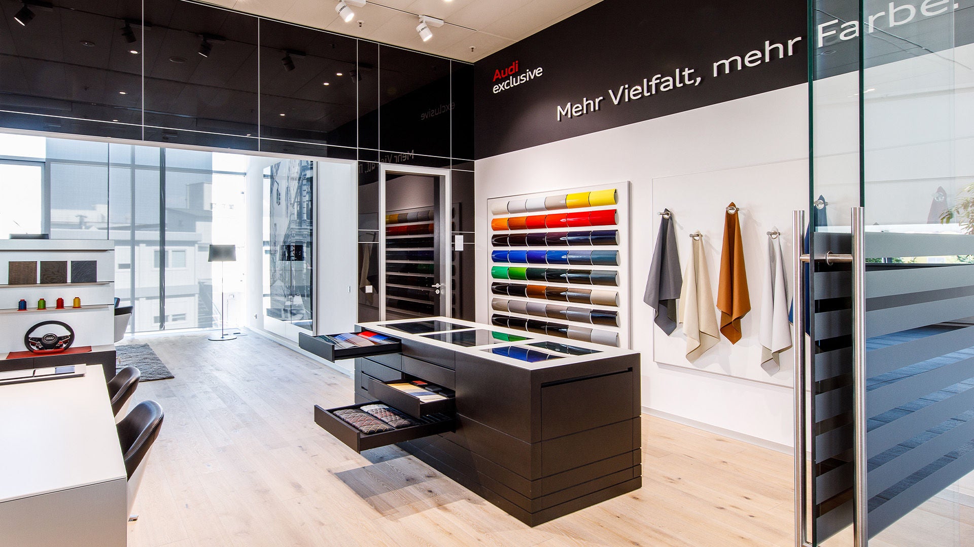 Showroom (Audi exclusive studio) with color samples and leather selection on the wall, open design workstation with drawers.