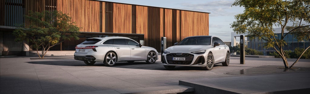 Side view of a blue Audi saloon parked in front of a modern building