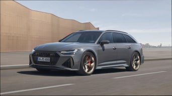 A grey Audi RS 6 Avant Performance driving on road with urban skyline in the background