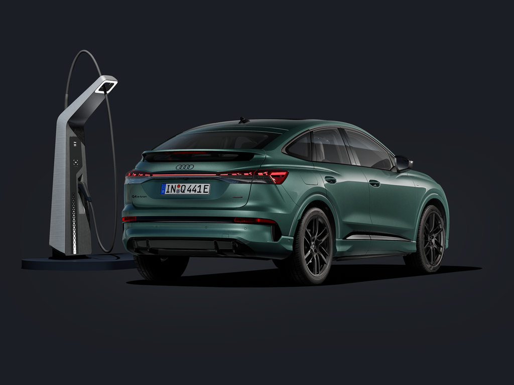 De Audi Q4 Sportback e-tron, schuin van achteren gezien tegen een donkere achtergrond, met daarnaast een modern laadstation.