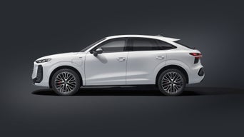 Side profile of a white Q3 SUV e-hybrid charging in the parking lot in front of a modern house.