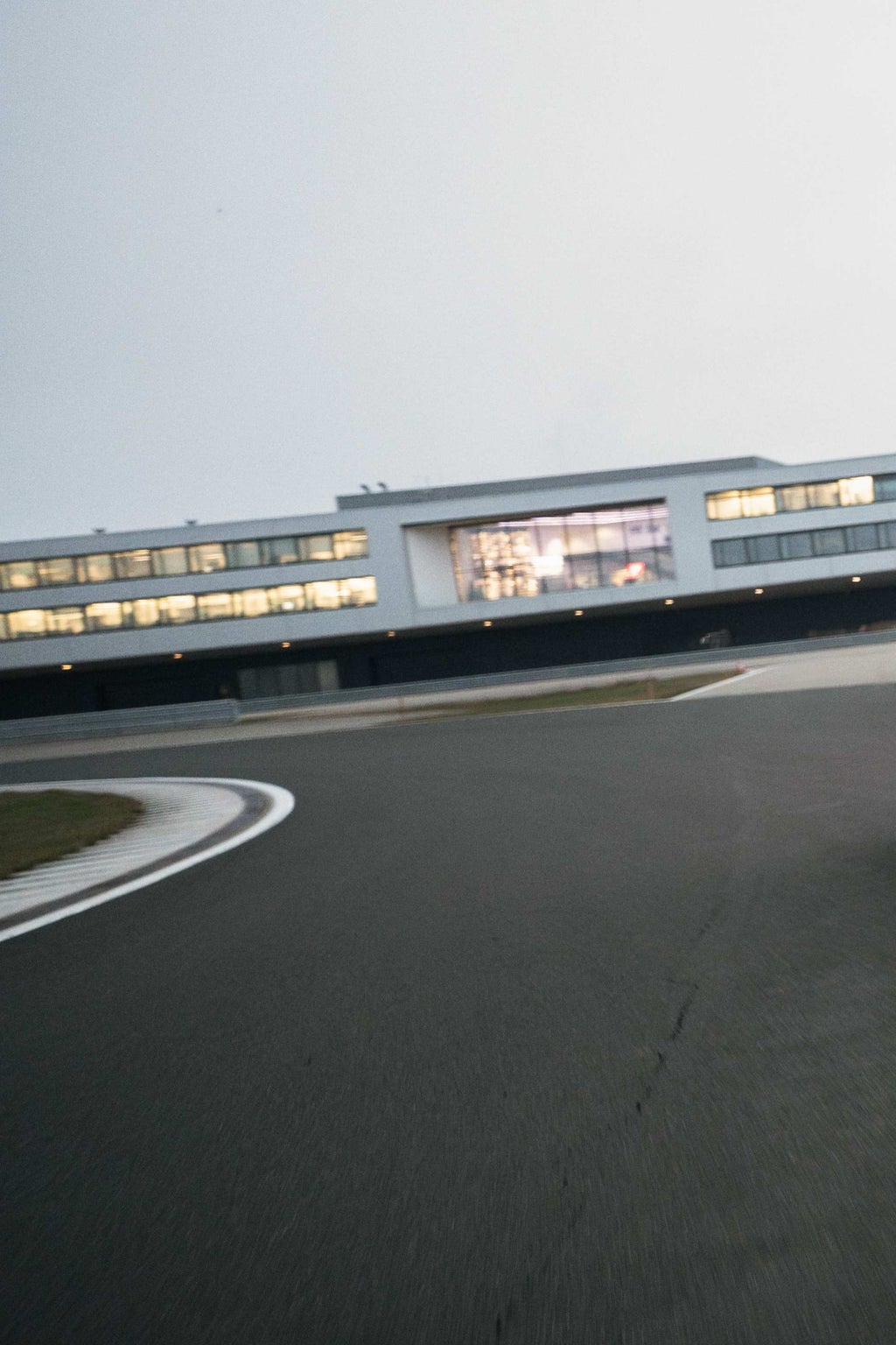 Asphaltkurve einer Teststrecke mit einem erleuchteten Gebäude im Hintergrund.