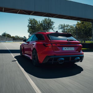Heckansicht des neuen Audi RS 5 Avant auf einer Rennstrecke fahrend.