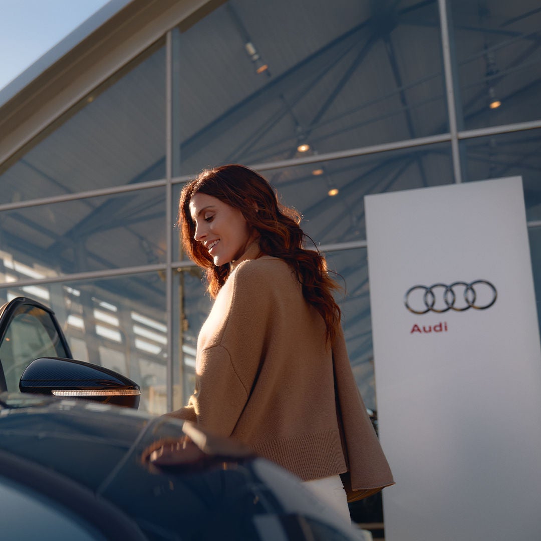 Close up of a woman walking near an Audi car's rear