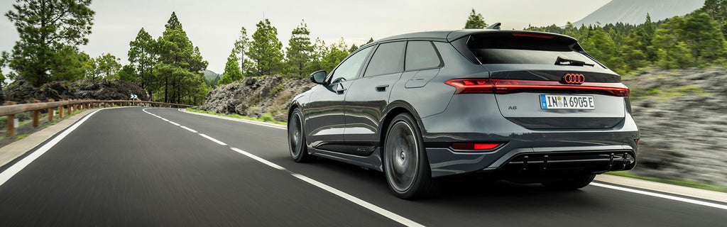 Rear view of the Audi A6 Avant e-tron on a road next to woods