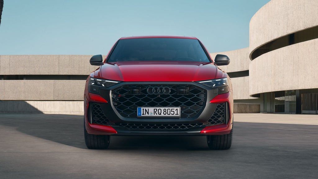 De RS Q8 Performance in chilirood metallic, geparkeerd voor een futuristisch gebouw.