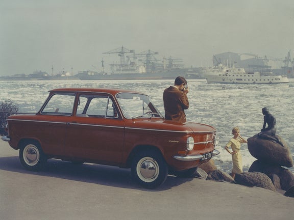 Ein Mann fotografiert eine Frau vor kleinen Meerjungfrau in Kopenhagen und lehnt dabei an einem roten NSU Prinz