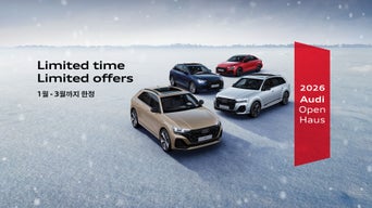 한 남성이 휴대전화 화면을 바라보고 있으며, 배경에는 아우디 모델이 주차되어 있습니다.